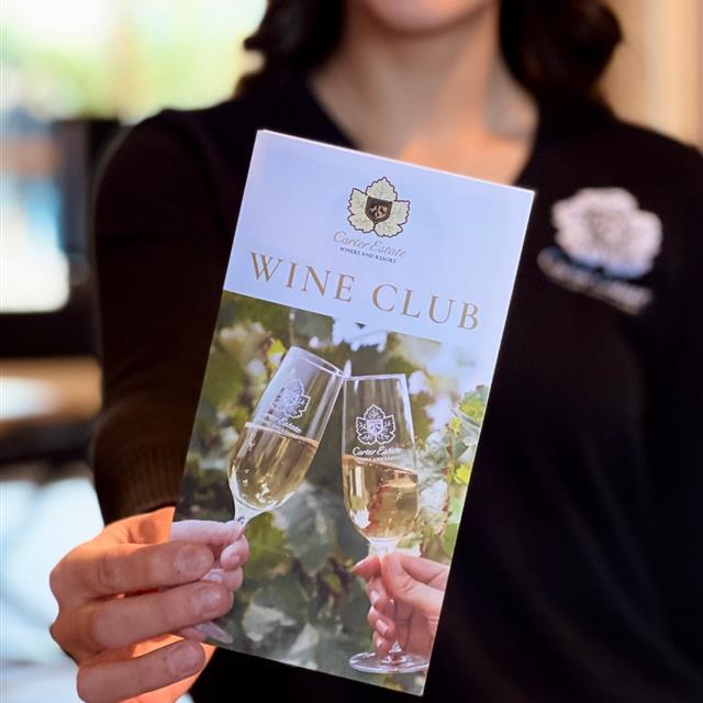 a woman holding a wine club brochure